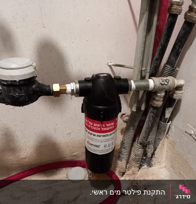 מד מים ומסנן מחוברים לצינורות על קיר